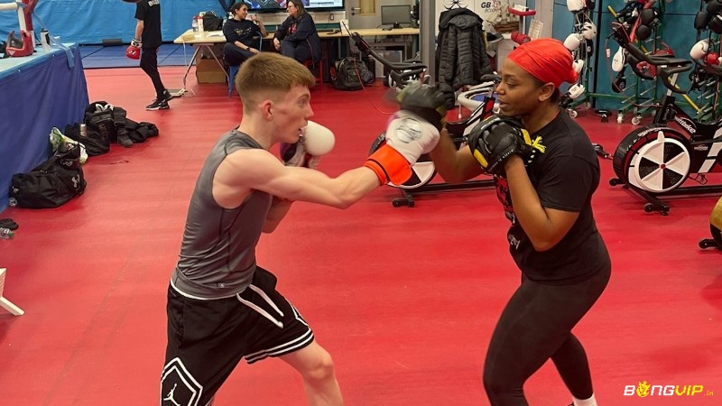 Các nữ võ sĩ trẻ tập luyện cùng huấn luyện viên trong phòng gym boxing